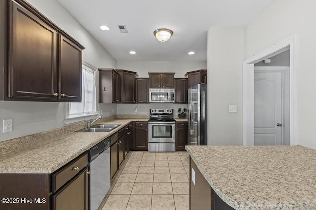 kitchen featuring light tile patterned flooring, stainless steel appliances, dark brown cabinetry, and sink