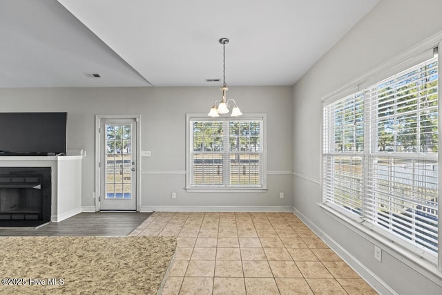 unfurnished dining area featuring light tile patterned floors and a notable chandelier