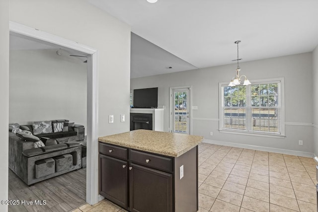 kitchen with decorative light fixtures, light tile patterned floors, dark brown cabinetry, and a notable chandelier