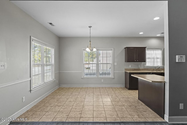 kitchen with decorative light fixtures, a notable chandelier, light tile patterned flooring, dark brown cabinets, and sink