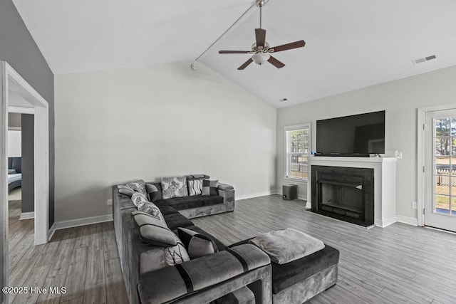 living room with hardwood / wood-style flooring, lofted ceiling, ceiling fan, and a healthy amount of sunlight