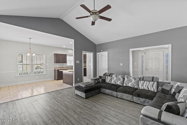 living room featuring ceiling fan with notable chandelier and high vaulted ceiling