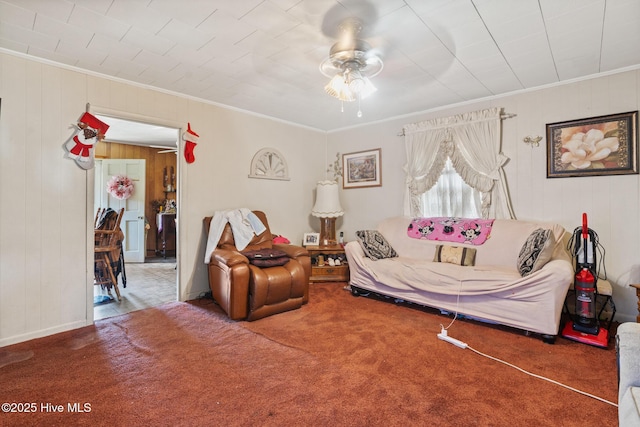 carpeted living room with ceiling fan, wooden walls, and ornamental molding