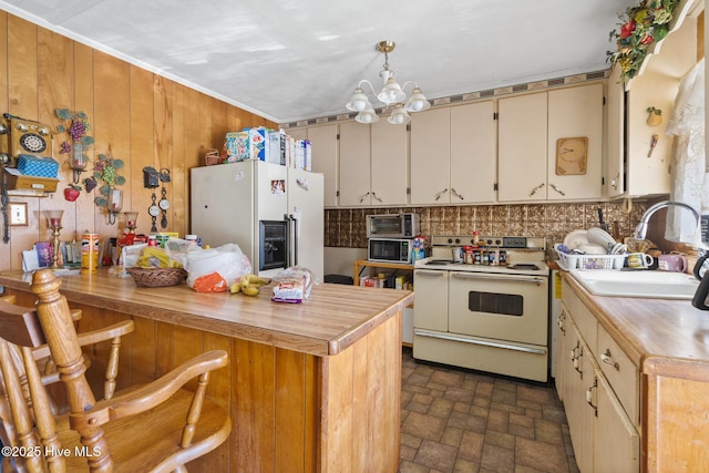 kitchen with pendant lighting, white appliances, wooden counters, sink, and a chandelier