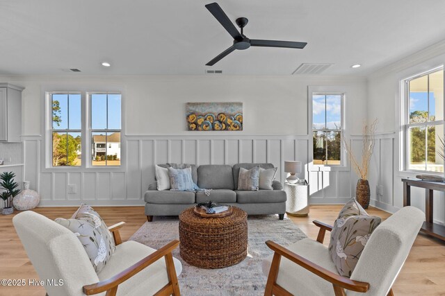 living room with crown molding, light hardwood / wood-style floors, and ceiling fan