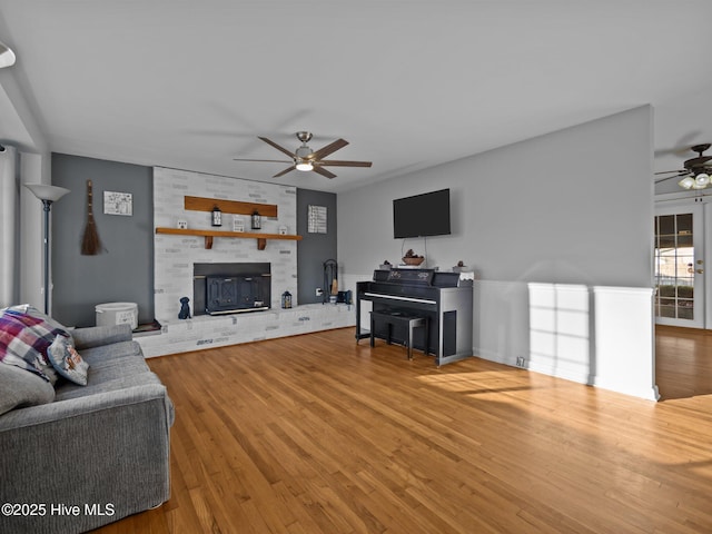 living room featuring a fireplace, wood-type flooring, and ceiling fan