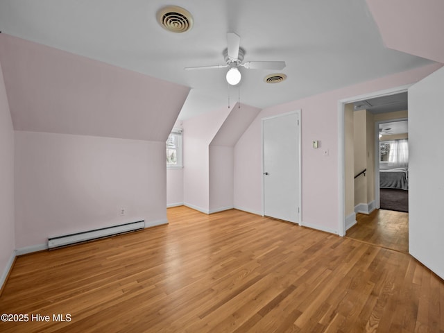 additional living space featuring vaulted ceiling, a baseboard radiator, ceiling fan, and light hardwood / wood-style floors