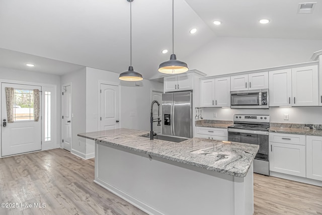 kitchen featuring stainless steel appliances, white cabinets, and a center island with sink