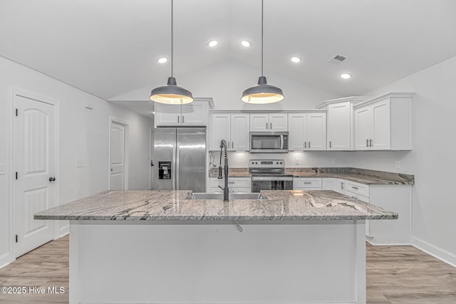 kitchen featuring pendant lighting, white cabinetry, stainless steel appliances, and a center island with sink