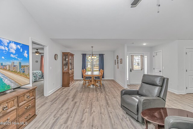 living room with ceiling fan with notable chandelier, a healthy amount of sunlight, and light hardwood / wood-style floors