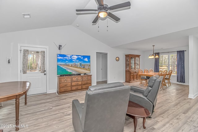 living room featuring ceiling fan with notable chandelier, vaulted ceiling, and light hardwood / wood-style flooring