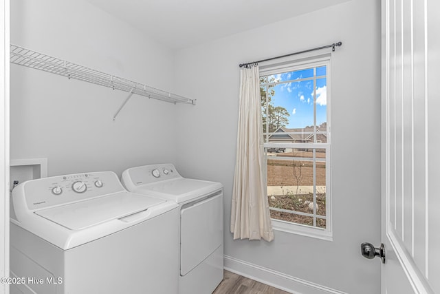 clothes washing area with washing machine and clothes dryer and light hardwood / wood-style floors