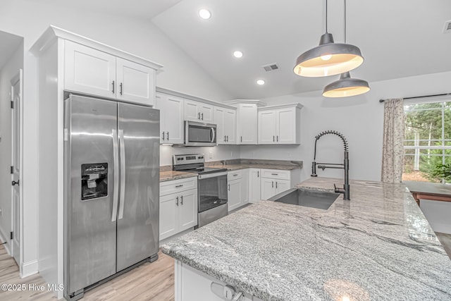 kitchen with sink, appliances with stainless steel finishes, light stone countertops, white cabinets, and decorative light fixtures