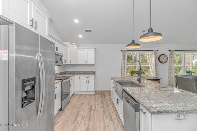 kitchen featuring sink, white cabinetry, hanging light fixtures, stainless steel appliances, and a center island with sink