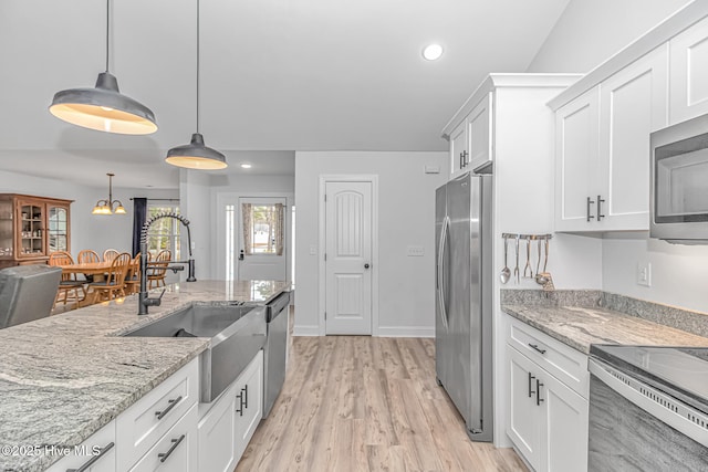 kitchen with sink, white cabinetry, stainless steel appliances, light stone countertops, and decorative light fixtures