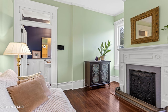 living area featuring a fireplace, baseboards, ornamental molding, and hardwood / wood-style floors