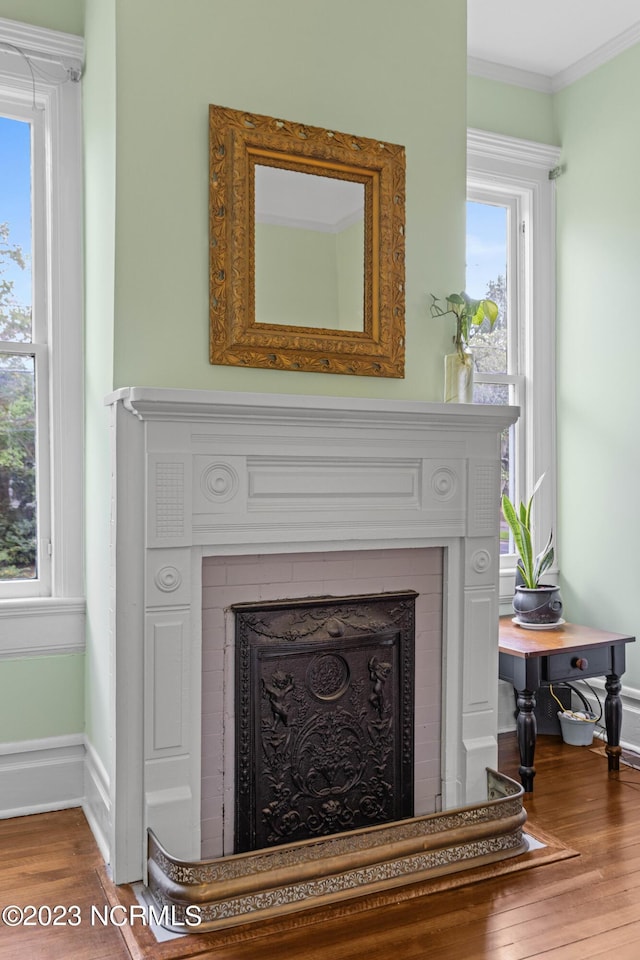 interior details featuring crown molding, baseboards, a fireplace, and wood finished floors