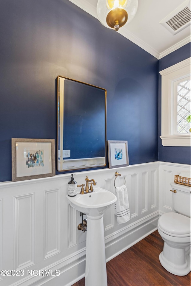 bathroom with a wainscoted wall, ornamental molding, wood finished floors, and visible vents