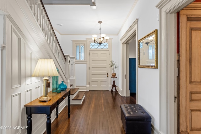 entryway featuring ornamental molding, stairs, a chandelier, and dark wood-style floors