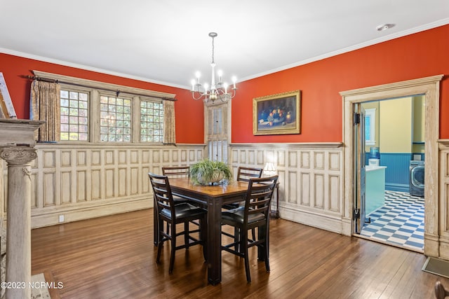 dining room featuring an inviting chandelier, wainscoting, a decorative wall, ornamental molding, and hardwood / wood-style flooring