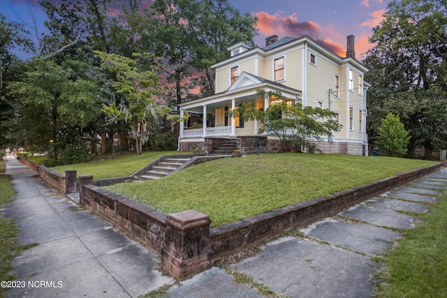 view of front of home with covered porch and a lawn