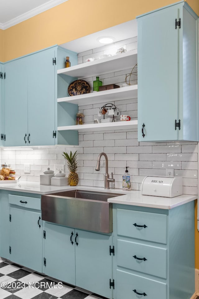 kitchen featuring crown molding, open shelves, a sink, blue cabinets, and backsplash