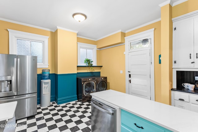 kitchen with appliances with stainless steel finishes, independent washer and dryer, white cabinets, and ornamental molding