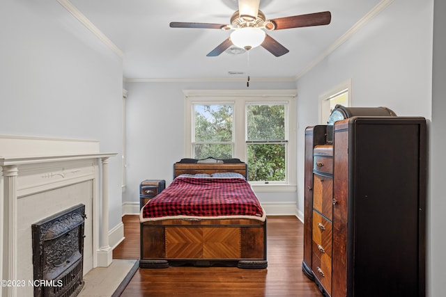 bedroom featuring ornamental molding, wood finished floors, a fireplace, baseboards, and ceiling fan