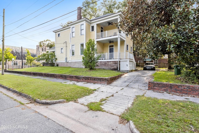 view of front of house with a porch, driveway, a ceiling fan, a chimney, and a front yard