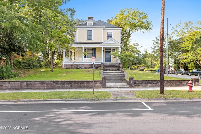 view of front of home with covered porch, stairway, and a front yard