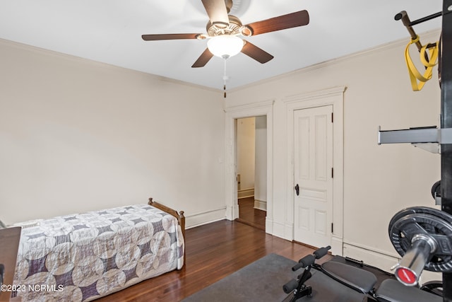 exercise area featuring ceiling fan, dark wood-type flooring, and ornamental molding