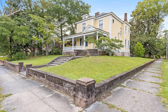 traditional style home featuring a front yard, covered porch, and a chimney