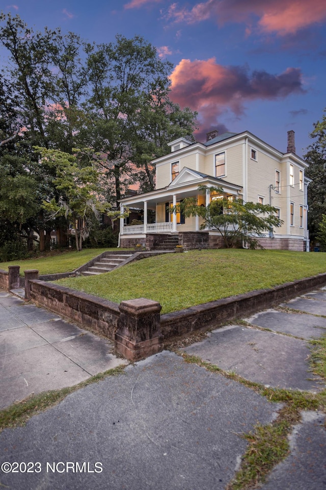 view of front of house with a chimney, a yard, and a porch