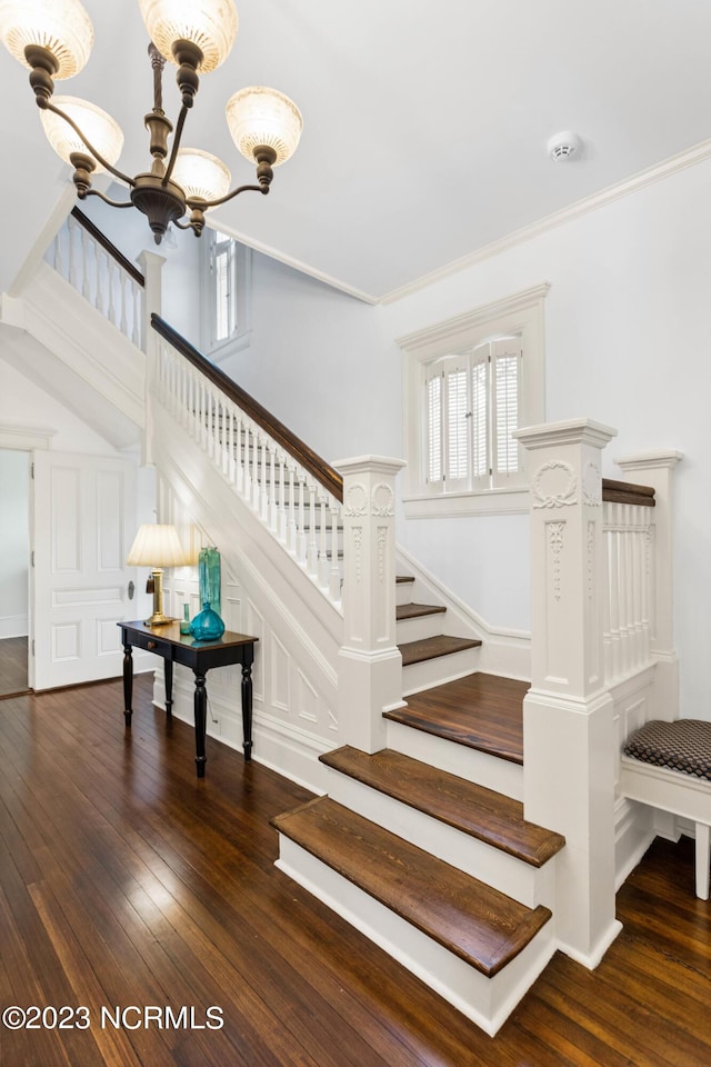 staircase featuring ornamental molding, wood finished floors, and a chandelier