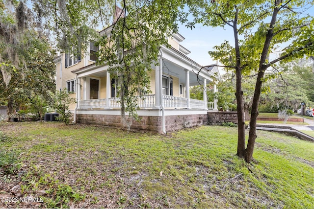 view of side of home with a porch, a yard, and central air condition unit