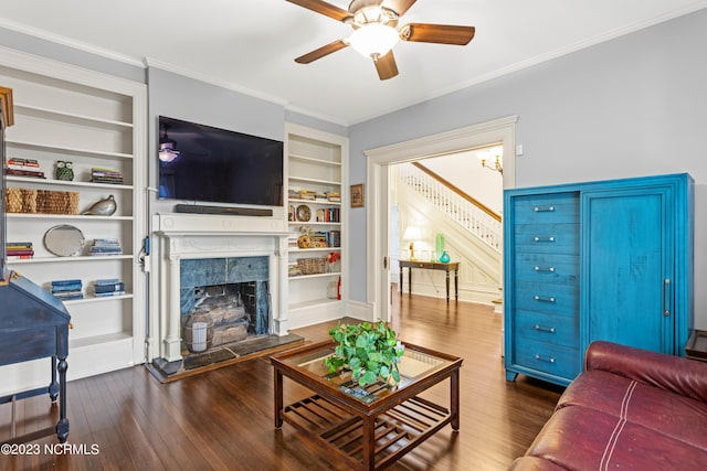 living area with ornamental molding, dark wood-style flooring, stairs, ceiling fan, and a high end fireplace