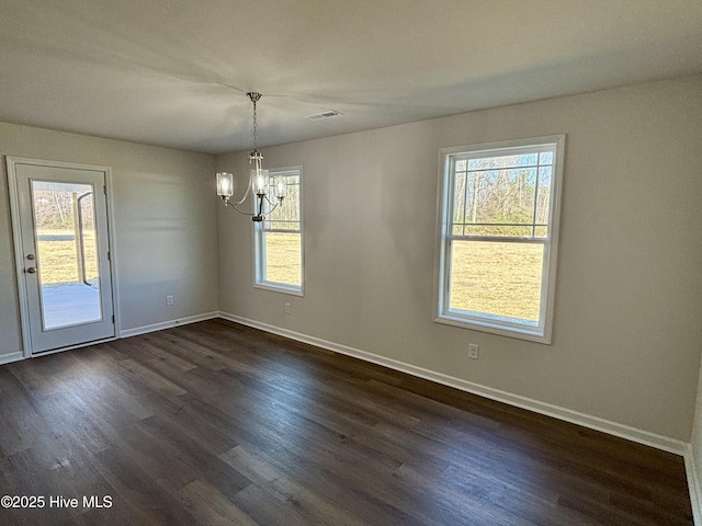 unfurnished dining area featuring dark wood-type flooring, a wealth of natural light, and a chandelier