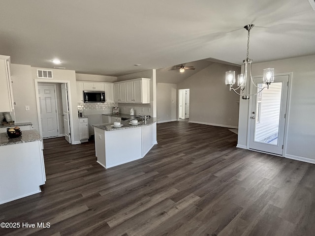 kitchen featuring white cabinetry, kitchen peninsula, hanging light fixtures, vaulted ceiling, and ceiling fan with notable chandelier