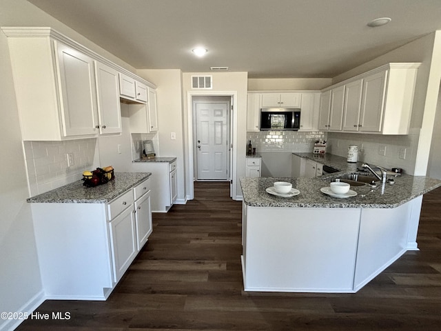 kitchen with white cabinetry, kitchen peninsula, and light stone counters