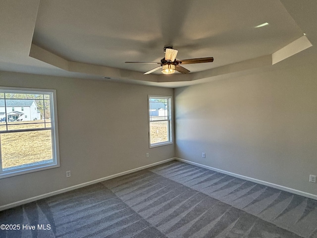 spare room with ceiling fan, a healthy amount of sunlight, carpet floors, and a tray ceiling