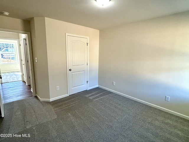 unfurnished bedroom featuring a closet and dark carpet