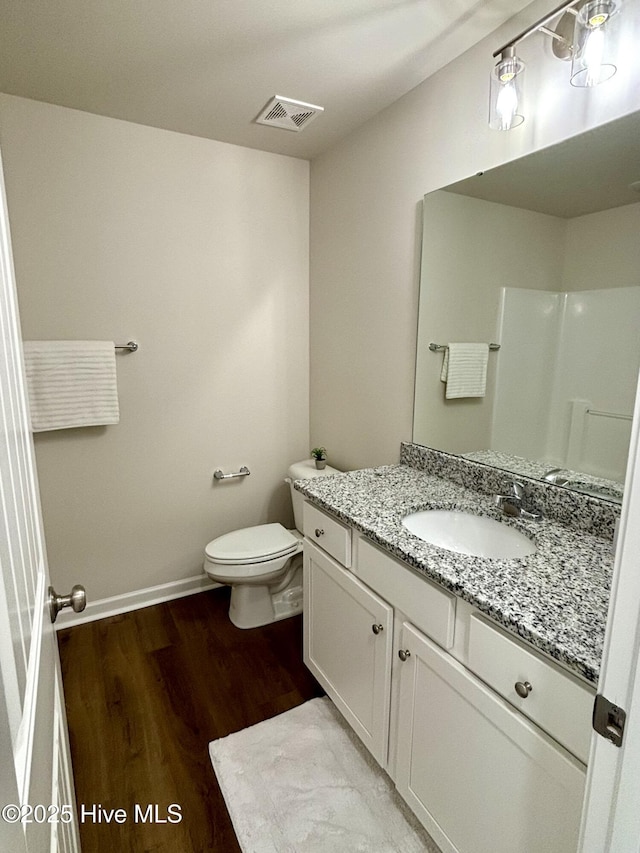 bathroom with toilet, vanity, a shower, and hardwood / wood-style floors