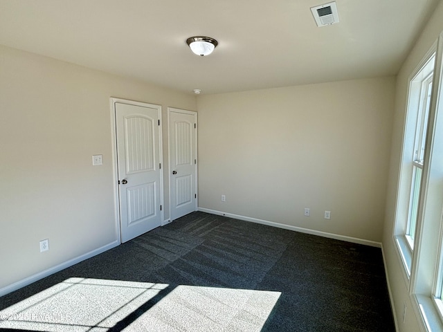 unfurnished bedroom with dark carpet