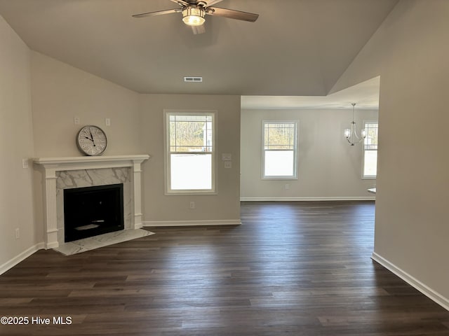 unfurnished living room featuring lofted ceiling, a fireplace, ceiling fan with notable chandelier, and dark wood-type flooring