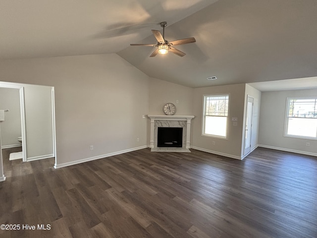 unfurnished living room featuring dark wood-type flooring, a healthy amount of sunlight, a fireplace, vaulted ceiling, and ceiling fan