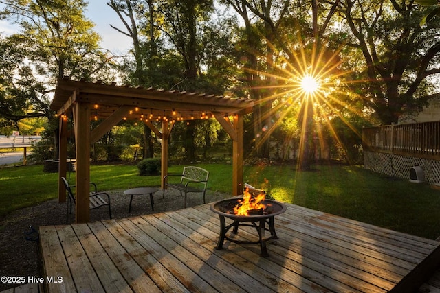 wooden deck featuring a lawn, an outdoor fire pit, and a pergola