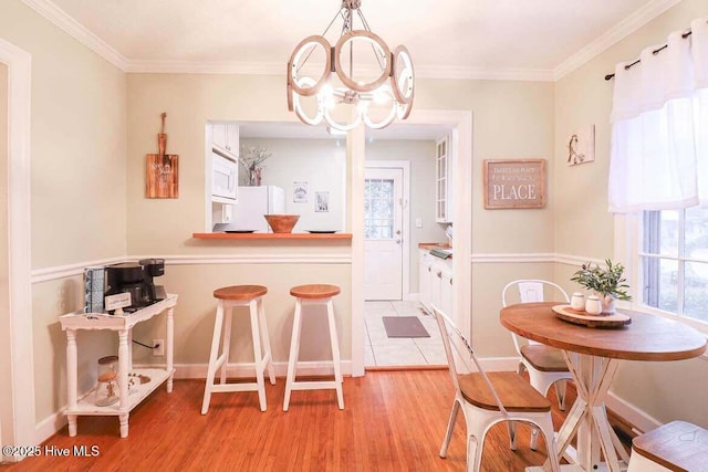 dining space with ornamental molding, a chandelier, and light hardwood / wood-style floors