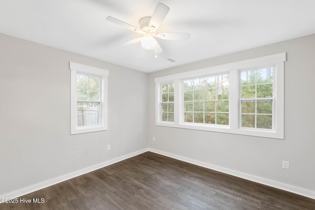 spare room with ceiling fan, a wealth of natural light, and dark hardwood / wood-style floors