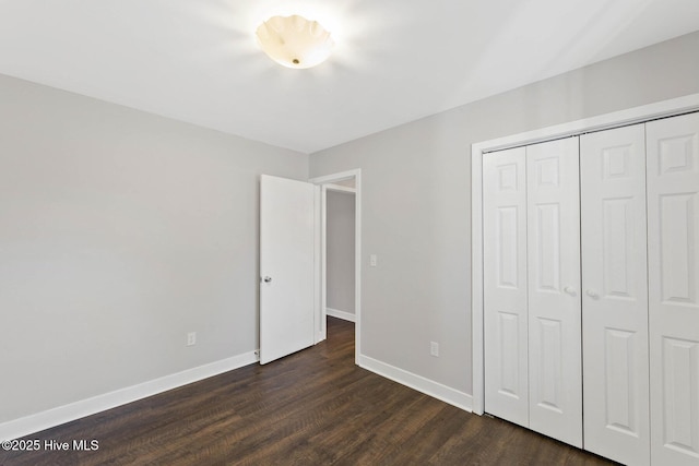 unfurnished bedroom with a closet and dark wood-type flooring