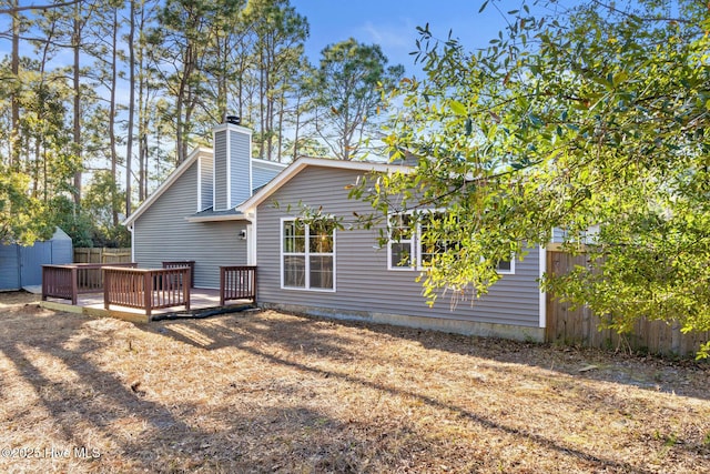 rear view of property featuring a shed and a wooden deck